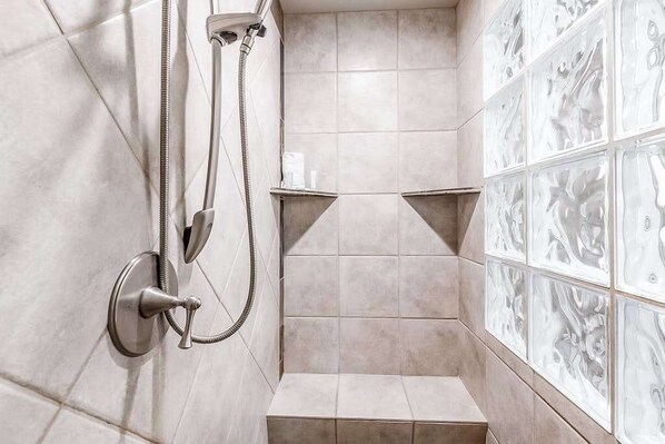 A shower area with a handheld showerhead, a wall-mounted faucet, and a tiled wall with decorative patterns. - 2BR Zion National Park - Hot tub - Pool (Santa Clara)