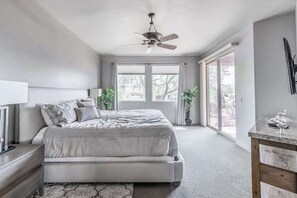 A bedroom with a bed, bedside table, nightstand, ceiling fan, large windows, and a view of the outdoors. - 2BR Zion National Park - Hot tub - Pool (Santa Clara)