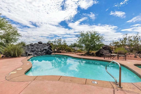 A swimming pool with a stone feature, surrounded by a patio area with chairs and a small table. - 2BR Zion National Park - Hot tub - Pool (Santa Clara)