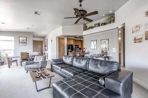 A modern living room with a leather sofa, a coffee table, and a ceiling fan. - 2BR Zion National Park - Hot tub - Pool (Santa Clara)