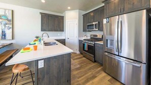 Una cocina moderna con armarios de madera oscura, electrodomésticos de acero inoxidable y una encimera blanca.