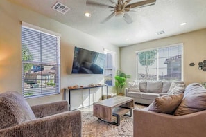 Ein Wohnzimmer mit Deckenventilator, Flachbildfernseher und Sofa.