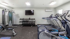 Een fitnessruimte met loopbanden, krachtapparaten en gewichten.