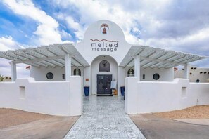 Ein Gebäude mit weißer Fassade und einem Schild, auf dem 'melted massage' steht.