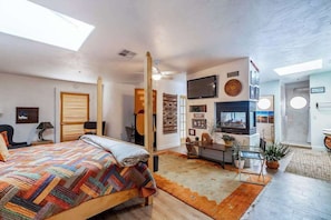 A spacious bedroom with a large bed, a TV, a desk, and a dining area. - Stylish 1BR Zion National Park - Patio - Pool (St. George)