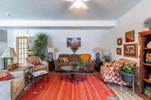 A living room with a sofa, armchairs, a coffee table, and a red rug. - Stylish 1BR Zion National Park - Patio - Pool (St. George)