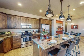 Eine moderne Küche mit Holzschränken, Edelstahlgeräten, einer Granitarbeitsplatte und Pendelleuchten.