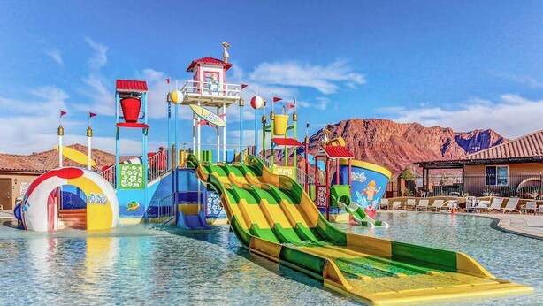 Ein Wasserpark mit zahlreichen Wasserrutschen und Wasserspielen, umgeben von Bergen.