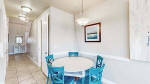 A dining area with a round table and four chairs, a pendant light, and a framed picture on the wall. - Spacious townhome with shared pool & hot tub (Washington)