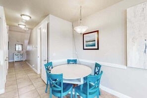 A dining area with a round table and four chairs, a pendant light, and a framed picture on the wall. - Spacious townhome with shared pool & hot tub (Washington)
