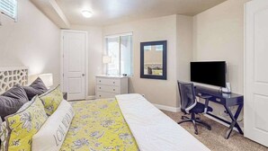 A bedroom with a bed, a desk, a chair, a television, a ceiling fan, and a door. - Spacious townhome with shared pool & hot tub (Washington)