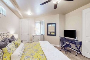 A bedroom with a bed, a desk, a chair, a television, a ceiling fan, and a door. - Spacious townhome with shared pool & hot tub (Washington)