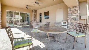 An outdoor patio with a round table and chairs, a ceiling fan, and a stone wall. - Spacious townhome with shared pool & hot tub (Washington)