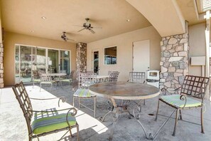 An outdoor patio with a round table and chairs, a ceiling fan, and a stone wall. - Spacious townhome with shared pool & hot tub (Washington)