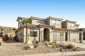 A two-story house with a garage, a driveway, and a landscaped front yard with rocks and plants. - Brand New 5BR Zion National Park - Patio (Washington)