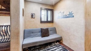 A room with a sofa, a window with bars, a wall with a decorative mural, and a staircase in the background. - Spacious 5BR Mountainview Zion National Park (Leeds)