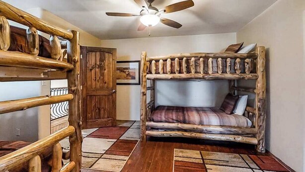 A rustic room with a bunk bed, a ceiling fan, and a wooden door. - Spacious 5BR Mountainview Zion National Park (Leeds)
