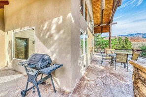 Eine überdachte Terrasse mit Grill, Sitzgelegenheit und Blick auf die umliegende Landschaft.