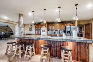 A kitchen with a central island, wooden bar stools, and pendant lighting. - Spacious 5BR Mountainview Zion National Park (Leeds)