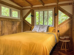 Una habitación con cama, ventana y techo de madera.