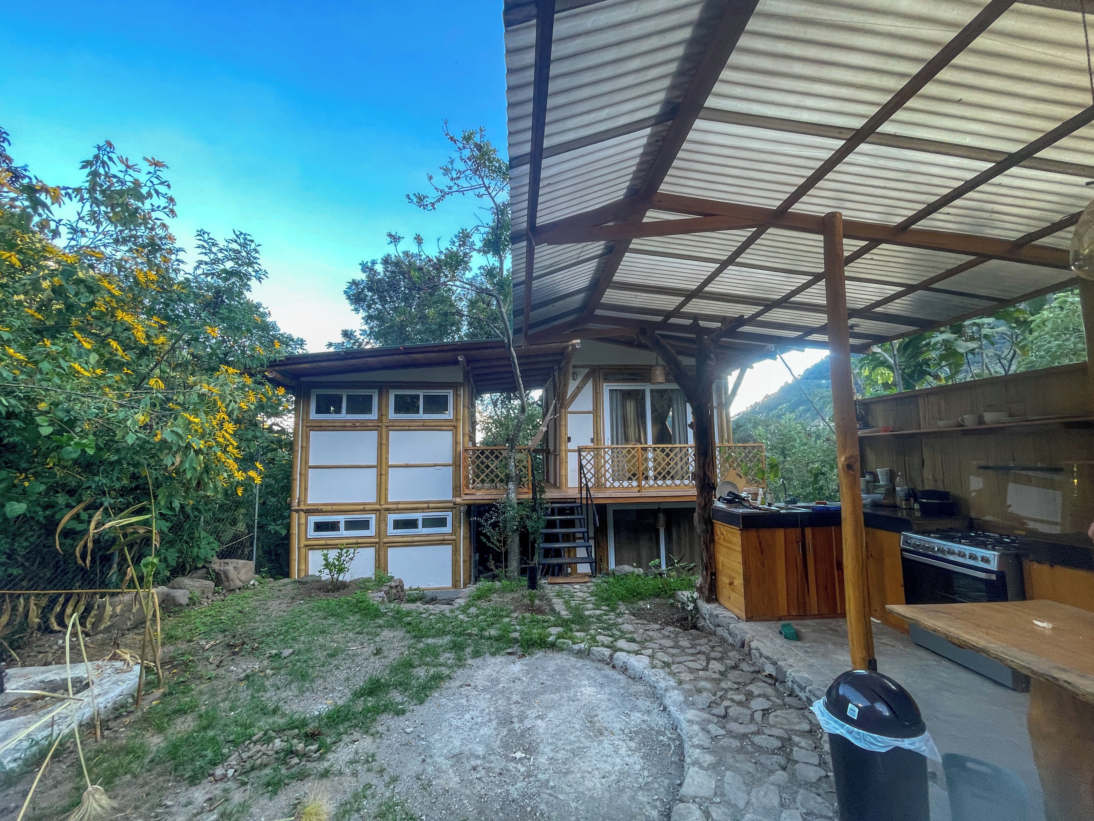Un edificio de dos pisos con un balcón, un sendero de piedra y una cocina.