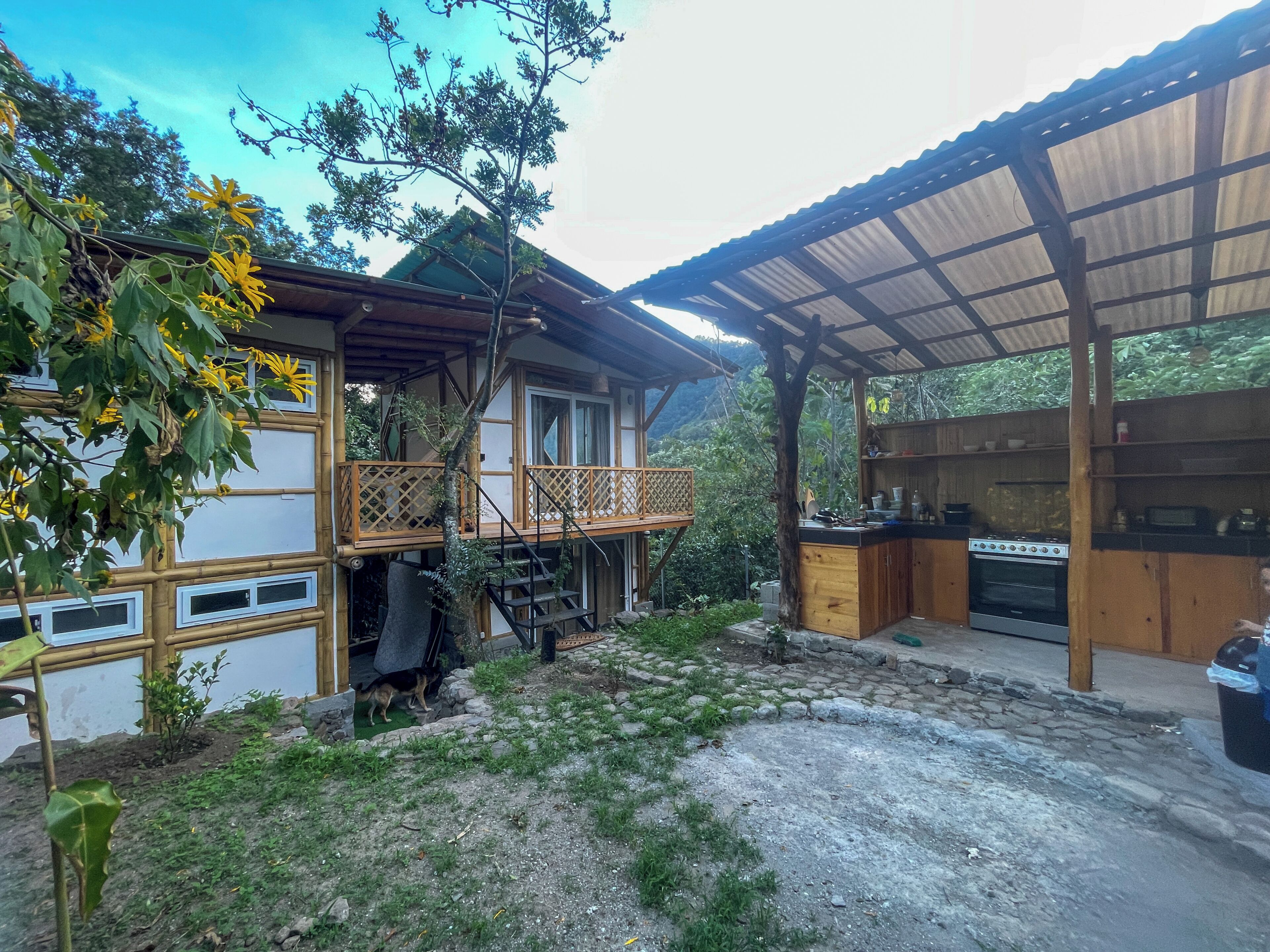 Une maison en bois à deux étages, dotée d’un balcon, d’un espace cuisine et d’un espace extérieur abrité.