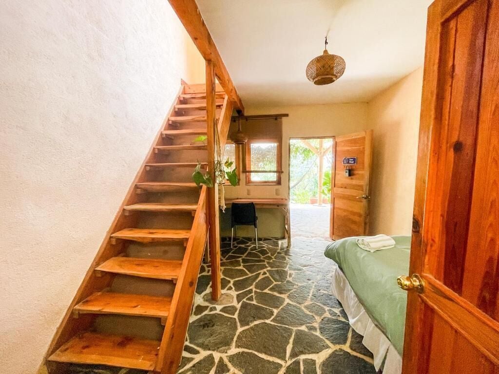 Una habitación con escaleras de madera, una cama, un escritorio y una ventana.