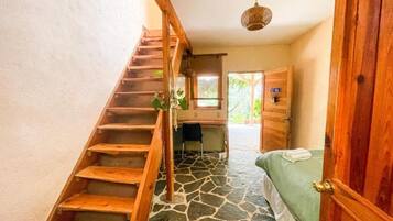 Una habitación con escaleras de madera, una cama, un escritorio y una ventana.