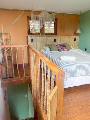 Un dormitorio con cama de madera, una ventana con vistas y una escalera.