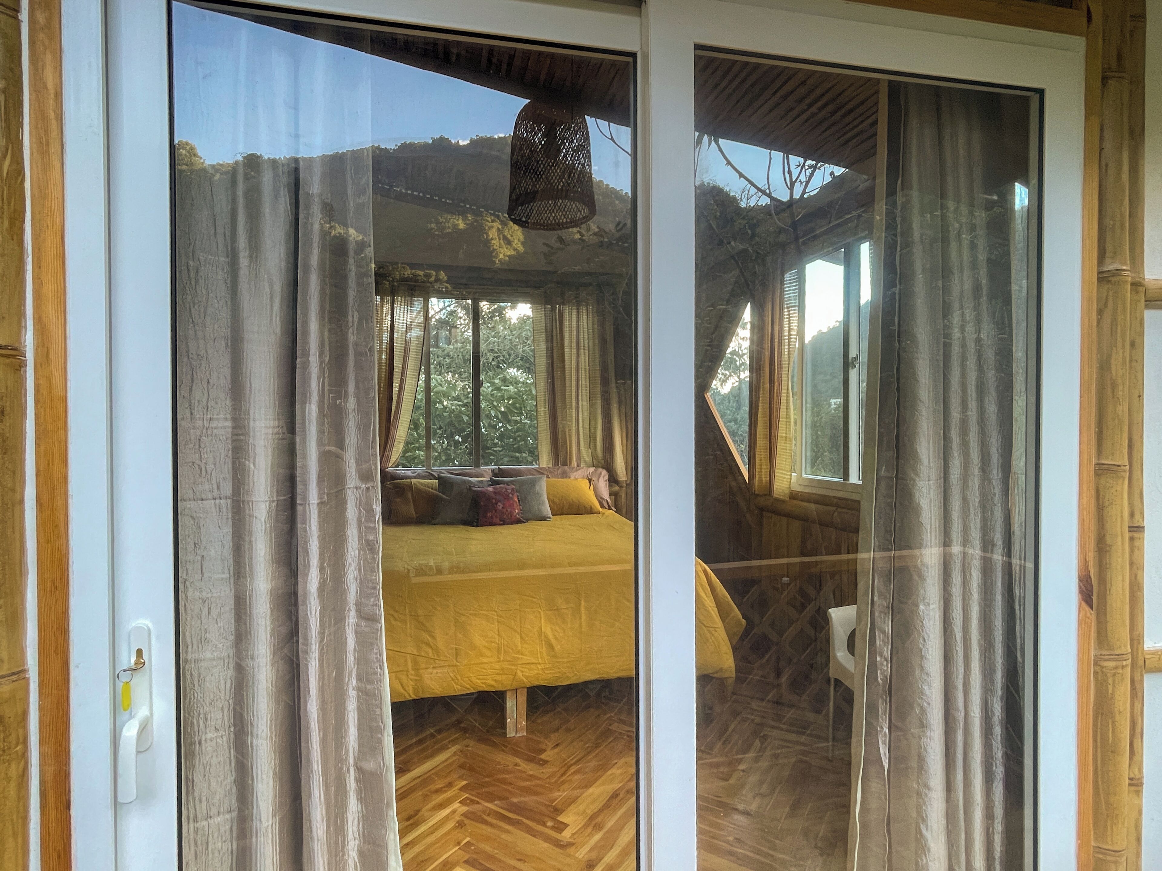 A room with a bed, wooden flooring, and a view of the outdoors.