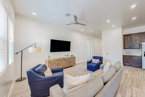 Ein Wohnzimmer mit einer Couch, einem Fernseher und einem Deckenventilator.