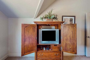 A wooden entertainment center with a television, a plant, and a framed picture. - 5BR with deck, grill, fireplace, pool, & hot tub (St. George)