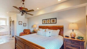 A bedroom with a large bed, a ceiling fan, bedside lamps, and framed pictures on the wall. - 5BR with deck, grill, fireplace, pool, & hot tub (St. George)