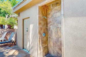 Uma área de spa com chuveiro, porta e espaço de estar com espreguiçadeiras.