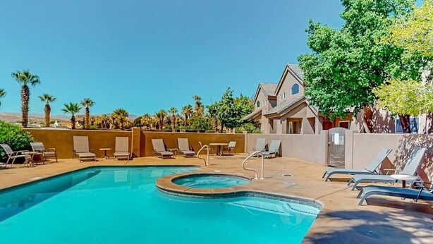 A swimming pool with lounge chairs and a building with a pitched roof. - 5BR with deck, grill, fireplace, pool, & hot tub (St. George)
