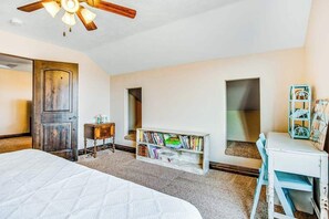 Ein Schlafzimmer mit einem Bett, einem Holzschrank, einem Bücherregal, einem Schreibtisch und einem Deckenventilator.