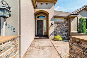 A house with a stone facade, a number '4072' on the wall, a front door, and a small garden with a yellow bush. - Lovely 4BR Mountainview Zion National Park (Hurricane)