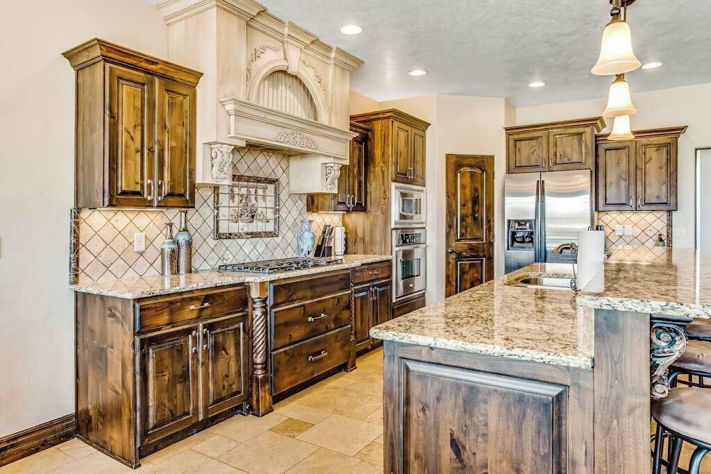 A kitchen with wooden cabinets, granite countertops, and stainless steel appliances.