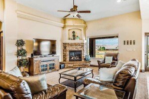 A living room with a fireplace, leather furniture, a television, and a view of the outdoors. - Lovely 4BR Mountainview Zion National Park (Hurricane)
