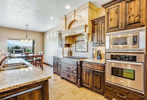 A kitchen with a central island, built-in ovens, and a view to the dining area. - Lovely 4BR Mountainview Zion National Park (Hurricane)