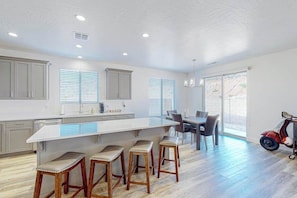 Una cocina moderna con una isla grande, taburetes de bar y un comedor con mesa y sillas.