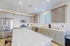 A modern kitchen with stainless steel appliances, a large island, and light-colored cabinetry. - 3BR dog-friendly house with grill, patio, AC (Washington)