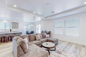 A spacious living area with a sectional sofa, a round coffee table, and a kitchen in the background. - 3BR dog-friendly house with grill, patio, AC (Washington)