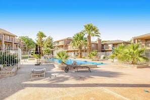 A hotel pool area with lounge chairs, palm trees, and a clear blue sky. - Sunny 2BR Mountainview Zion National Park (St. George)