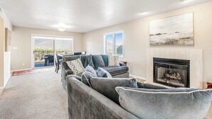 A living room with a fireplace, a sofa set, and a dining area with a view. - Sunny 2BR Mountainview Zion National Park (St. George)