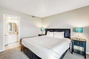 A bedroom with a large bed, a nightstand with a lamp, a dresser, and a mirror. - Sunny 2BR Mountainview Zion National Park (St. George)