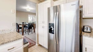 A kitchen with a stainless steel Whirlpool refrigerator, white cabinetry, and a granite countertop. - Sunny 2BR Mountainview Zion National Park (St. George)