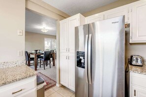 A kitchen with a stainless steel Whirlpool refrigerator, white cabinetry, and a granite countertop. - Sunny 2BR Mountainview Zion National Park (St. George)