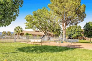 A playground with a swing set and a bench, surrounded by a fence and trees. - Sunny 2BR Mountainview Zion National Park (St. George)