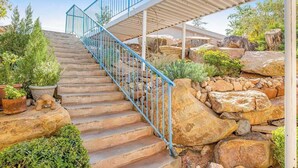 A staircase with a metal railing leading to a covered area with a view of a rocky landscape. - Sunny 2BR Mountainview Zion National Park (St. George)